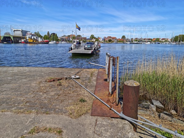 View of Germany's smallest town Arnis on the Schlei, grinding ferry, cable ferry for people and cars, wire ropes, transport technology, landing stage, shipyard, tugboat, marina with sailing boats, blue sky, sunshine, Sundsacker, Winnemark, landscape Schwansen, Schleswig-Holstein, Germany