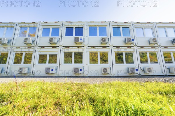 Several white containers with windows and air conditioning units stand on a green meadow, Beermiß refugee accommodation centre, Calmbach, Black Forest, Germany