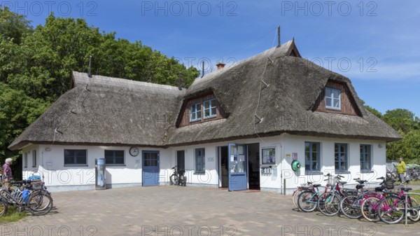 White, traditional thatched roof house with bicycles in front of it under a blue sky, Rügen, Hiddensee