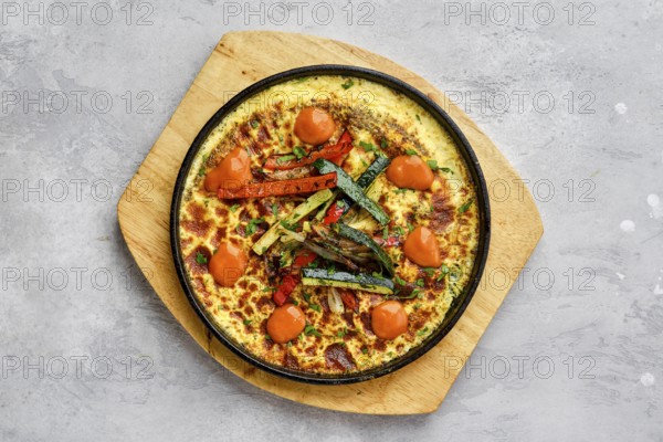 Top view of eggs with bell pepper and zucchini baked in oven in cast-iron skillet