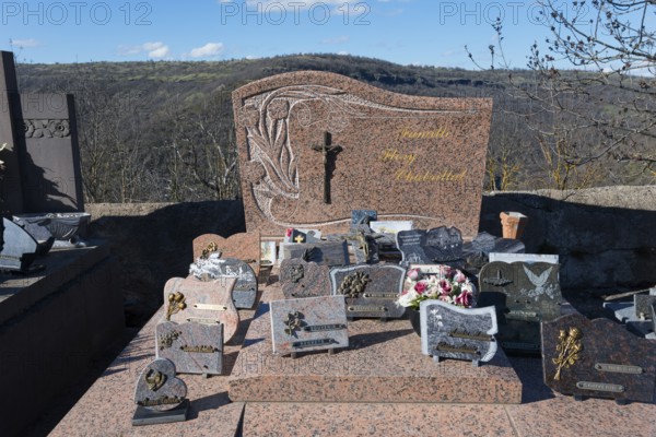 Grabsteine und Blumenschmuck auf einem Friedhof in einer hügeligen Landschaft mit einem christlichen Kreuz, Friedhof, Léotoing, Leotoing, Haute-Loire, Auvergne-Rhône-Alpes, Auvergne-Rhone-Alpes, Frankreich