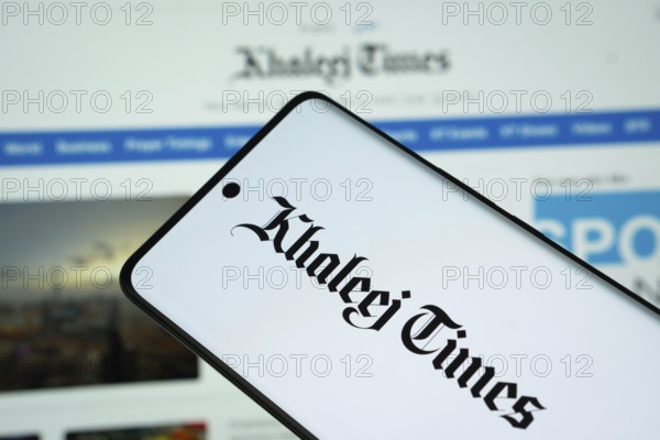 The logo of the newspaper khaleej times is displayed on a smartphone screen, and the website khaleej times is visible on a computer screen in the background
