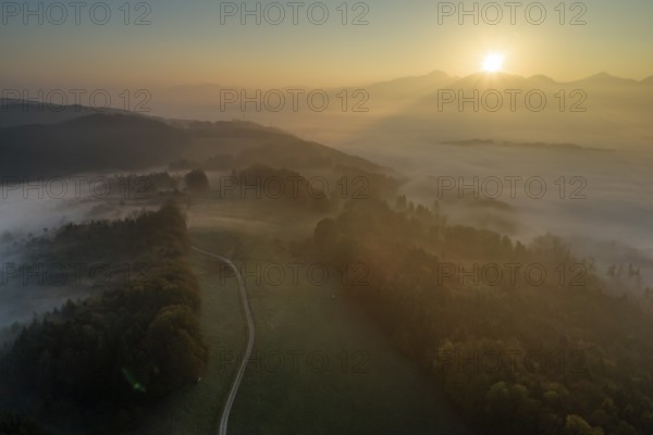 Aerial view of a mountain landscape over clouds, fog, sunrise, backlight, autumn, view of Kochler mountains, Alpine foothills, Bavaria, Germany