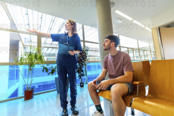 Female nurse holding a clipboard, providing instructions to a male patient seated in a bright, modern waiting room of a healthcare facility