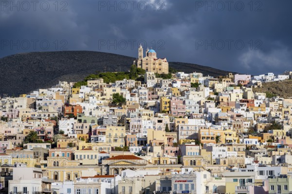 View of the town of Ermoupoli with pastel-coloured houses, on the hill Anastasi Church or Church of the Resurrection, dramatic cloudy sky, Ermoupoli, Syros, Cyclades, Greece