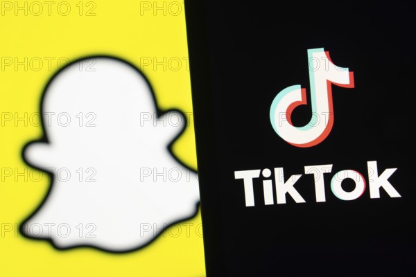 Tiktok logo is seen on a smartphone and Snapchat in the background