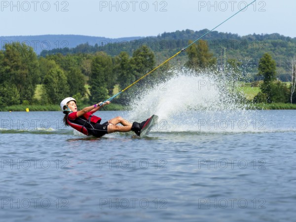 Boy or girl, summer holiday with wakeboard, water splashes, red life jacket, water skiing and wakepark, Stráž pod Ralskem, Czech Republic