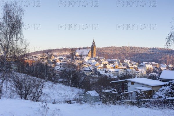Winter town view with St Wolfgang's Church and Gleesberg in the evening light, Schneeberg in the Ore Mountains, Saxony, Germany