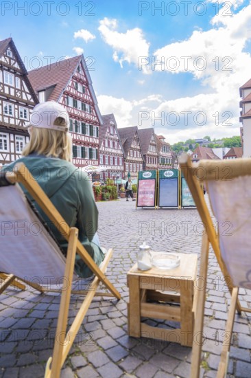 Person on a deckchair with a view of a street full of half-timbered houses, Calw, Black Forest, Germany