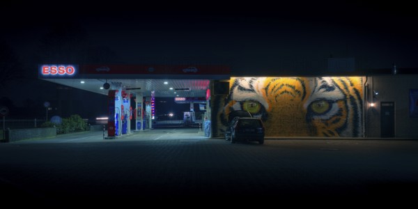 View of a petrol station with a parked car in front of a painted facade at night, Nienburg, Lower Saxony, Germany