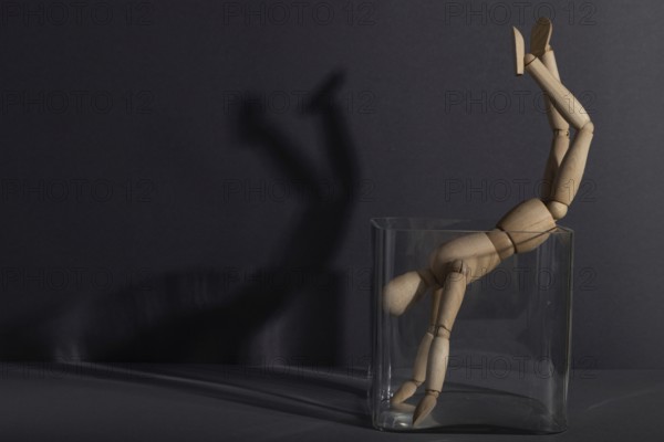 Wooden mannequin in a glass cube on gray background. captivity, break rules, loneliness, depression disorder concept. copy space