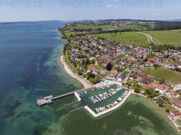 Luftbild von der Bodenseegemeinde Hagnau, Winzerdorf und beliebter Ferienort am Bodensee, dahinter Rebhänge, auf denen hauptsächlich die Weinsorten Müller Thurgau und Blauer Burgunder angebaut werden. Am Seeufer der am 23.Mai 2025 eingeweihte, neue Westhafen, Yachthafen mit der Schiffanlegestelle, Bodenseekreis, Baden-Württemberg, Deutschland