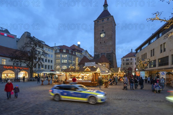Christmas market, winter night at Jakobsplatz, behind White Tower, in front a passing police car, Nuremberg, Middle Franconia, Bavaria, Germany