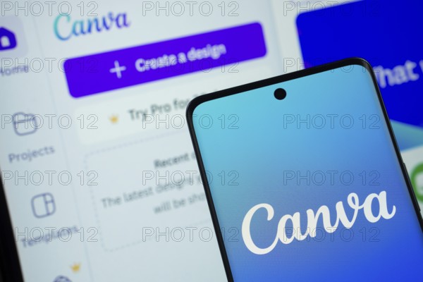 Canva logo is displayed on a smartphone screen, with the canva website visible on a computer screen in the background
