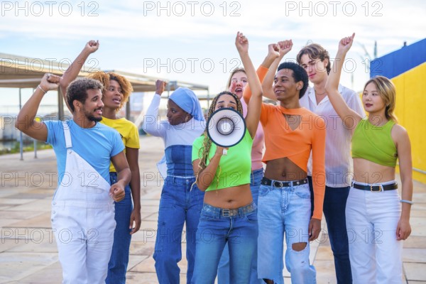 Multicultural and gender diverse young people yelling using a loudspeaker in a protest on an urban space
