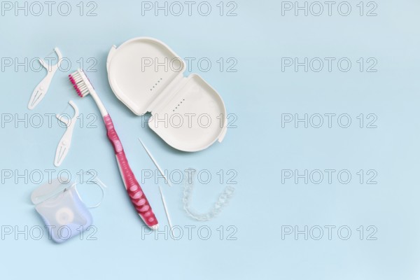 Top view of dental clear aligners, toothbrush, toothpicks and floss on blue background with copy space