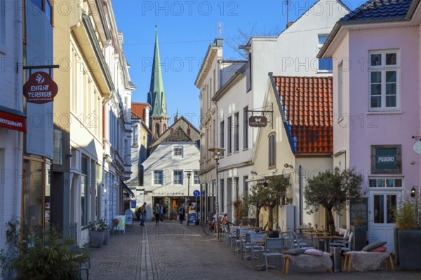 Oldenburg, Lower Saxony, Germany - Historic town centre, here the Burgstraße in the pedestrian zone, behind the St. Lamberti Church Oldenburg, a sight in the old town of Oldenburg. The pedestrian zone is characterised by historic buildings, small alleyways, a variety of owner-managed shops and restaurants. On the right, the Kleine Burg restaurant