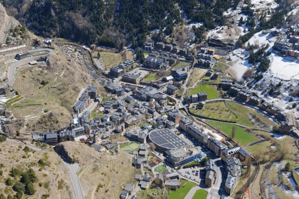 Blick auf eine kleine Stadt im Gebirgstal von Andorra mit verschneiten und grünen Flächen. Klar sichtbare Dächer und Straßen der Stadt, Mirador del Roc del Quer, Blick auf Canillo, Fürstentum Andorra, Pyrenäen