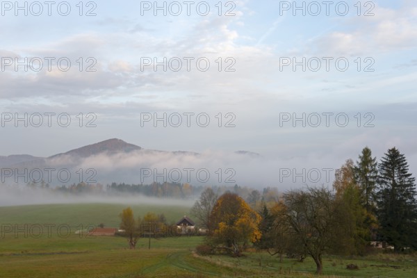 Fog in the valley, surrounded by trees and a small house, with a range of hills in the background, landscape near Kytlice, Lužické hory, Lusatian Mountains, Okres Decín, Ústecký kraj, Czech Republic
