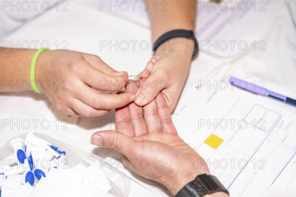 Close-up of a nurse checking blood sugar level by pricking the finger of a blood donor