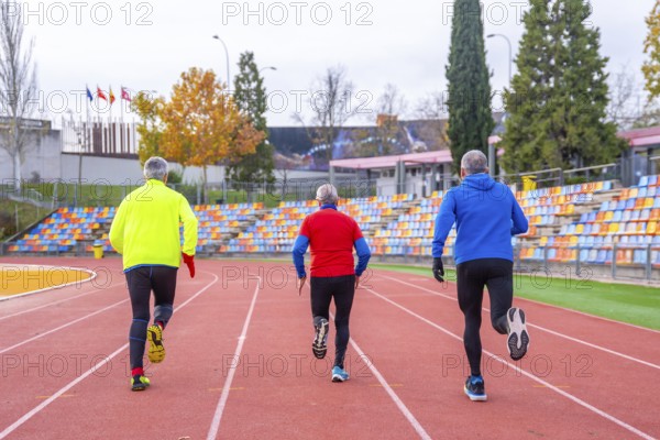 Rear view of three old sportive man sprinting in an athletics tack