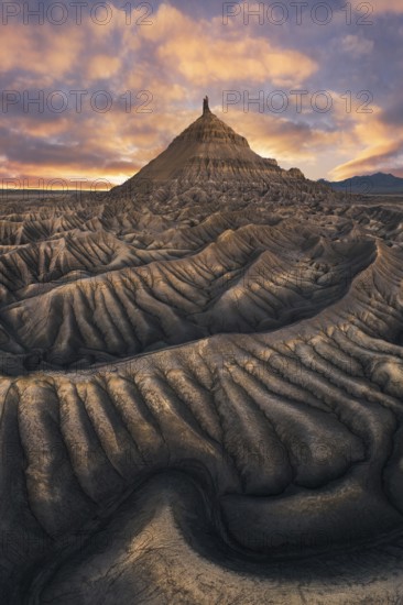 Majestic sunset illuminates the unique, rugged landscape of Factory Butte in Utah, showcasing dramatic undulating formations and a vibrant sky