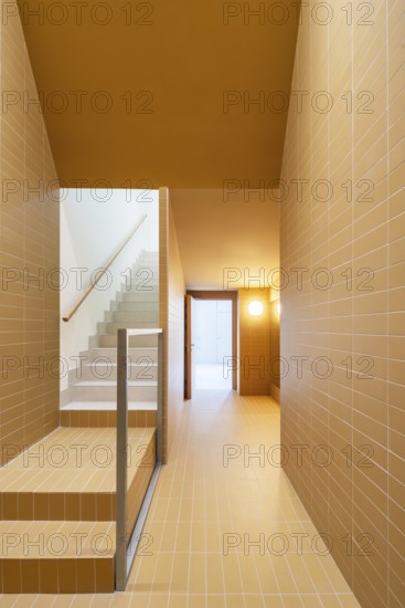 A modern staircase and hallway showcase sustainable architecture with vibrant orange and cream colors tiles, promoting a low-emission design and passive house efficiency standards