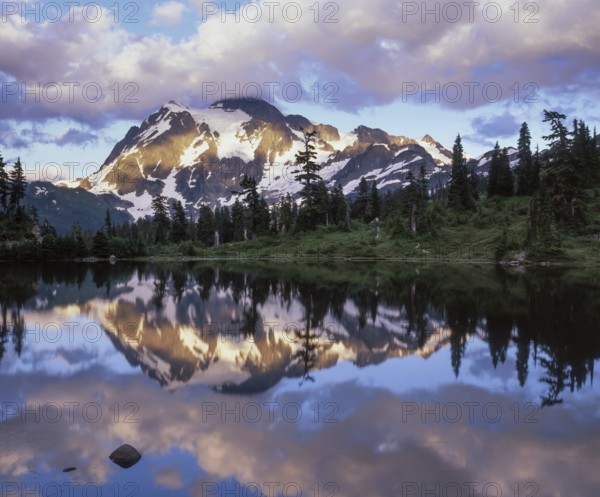 Twilight descends on Mount Shuksan in the North Cascades National Park as its snowy peak reflects beautifully in Picture Lake, creating a serene landscape