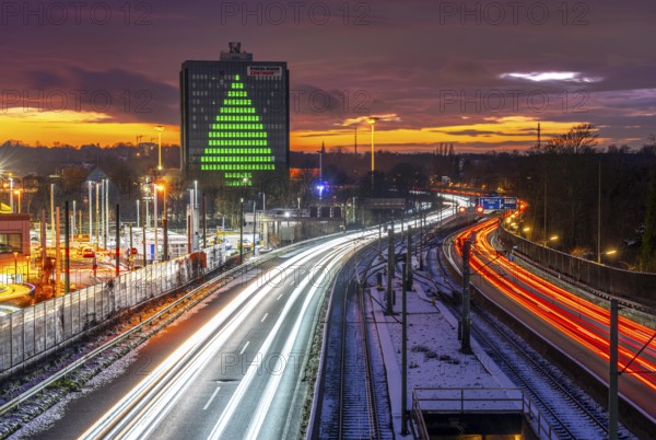 Autobahn A40, Ruhrschnellweg, between Essen and Mülheim an der Ruhr, evening traffic in winter, former, now vacant Stinnes high-rise building, at the Rhine-Ruhr Center, showing a green Christmas tree from illuminated windows at Christmas time, North Rhine-Westphalia, Germany