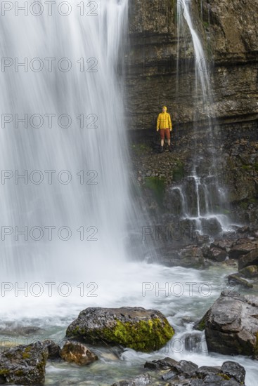 Adventure, Little hiker under large Cascata di Mezzo waterfall, long exposure, Vallesinella, Brenta, Trentino, Italy