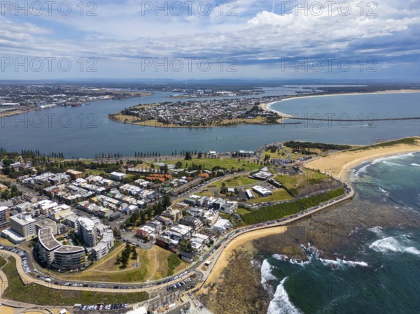 A breathtaking aerial view of Newcastle, New South Wales, showcasing the stunning coastline, urban landscape, and lush greenery under a dynamic sky