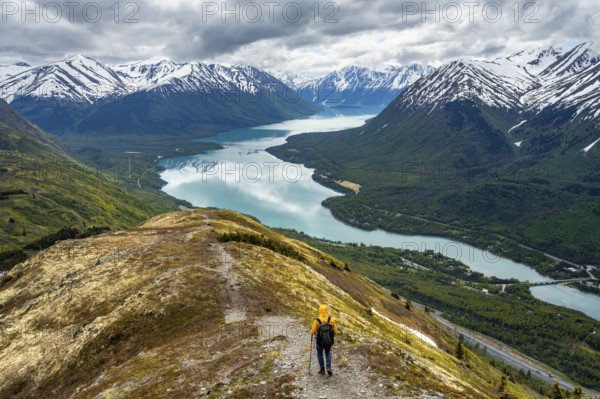 Climbers on a hiking trail on Slaughter Ridge, views of snowy mountains in spring and turquoise Lake Kenai Lake, Cooper Landing, Kenai Peninsula, Alaska, USA