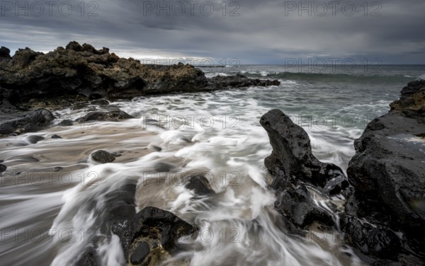 Waves blaze on the beach, rocky coast with volcanic stones, long exposure, Playa de la Pequeña, Punta Usaje, Lanzarote, Canary Islands, Spain