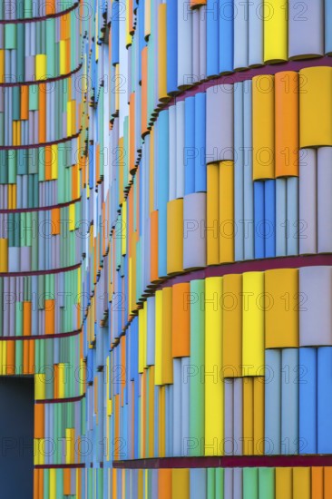 A striking image depicting the vivid, multicolored facade of a contemporary building, showcasing a dynamic array of vertical panels in various hues