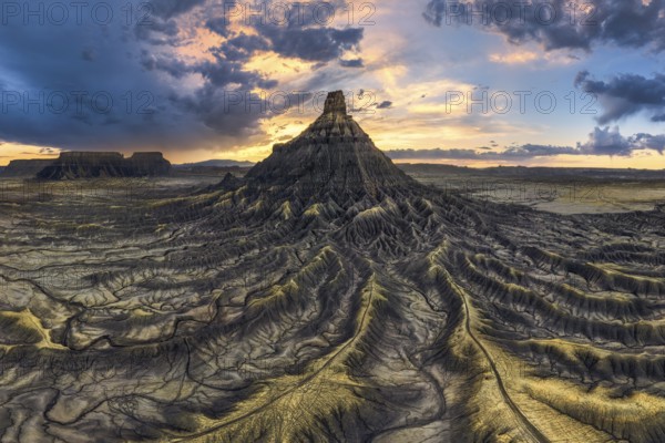 Dramatic sunset casts vibrant colors over the unique, eroded landscape of Factory Butte, Utah, highlighting the intricate patterns and textures of the badlands