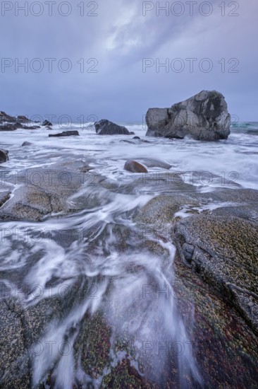 Rocks on beach of fjord of Norwegian sea in winter on sunset. Utakliev beach, Lofoten islands, Norway