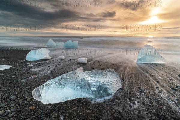 Captivating view of Diamond Beach in Iceland, showcasing stunning ice chunks scattered on the black sand with a breathtaking sunrise illuminating the scene