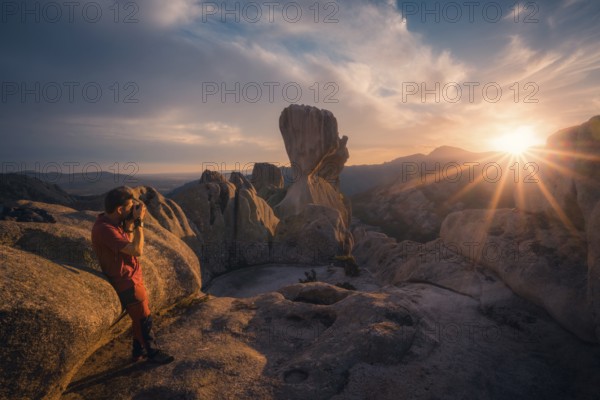A photographer captures the stunning sunset over Pedriza's iconic rock formations in the Sierra de Guadarrama, Madrid, with dramatic clouds and golden light filling the sky