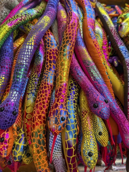 A vibrant collection of colorful plush snakes displayed in a Thai souvenir market. Each snake features unique, bright patterns, reflecting the lively culture of Thailand. Perfect for travelers