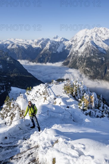 Tourist with camera on a hiking trail, Snow-covered summit of the Jenner with viewing platform in autumn, view of the sea of clouds and Watzmann, Berchtesgaden National Park, Berchtesgaden Alps, Schönau am Königssee, Berchtesgadener Land, Bavaria, Germany