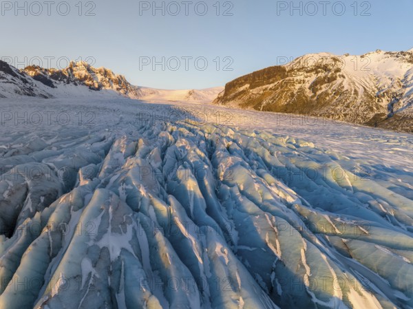 The stunning beauty of the Skaftafell Glacier during winter. The sunlight accentuates the rugged ice formations, creating a mesmerizing landscape of serene, icy grandeur
