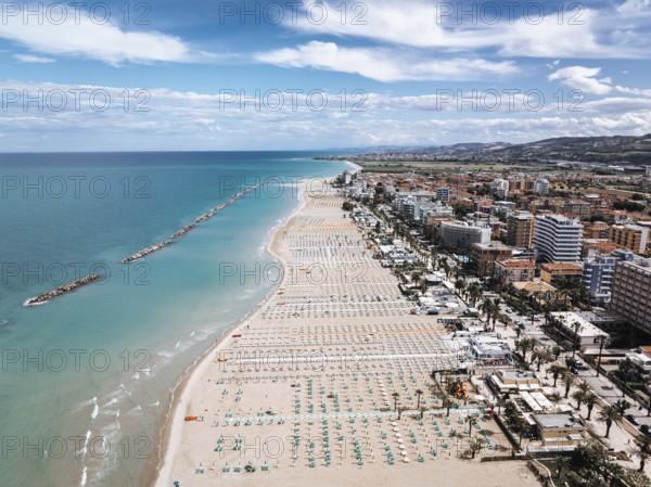 Stunning aerial shot of San Benedetto, Italy, showcasing its expansive sandy beaches, vibrant seaside town, and clear blue waters under a broad sky with scattered clouds