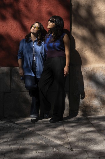 A multiethnic lesbian couple shares an intimate moment outdoors, exuding warmth and unity. The image highlights diversity, love, and LGBTQIA+ pride in a vibrant setting