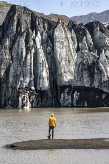 Tourist at the lakeside of a glacier lagoon, glacier tongue with crevasses and lake, Sólheimajökull, South Iceland, Iceland