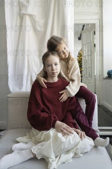 Two siblings share a tender moment indoors, capturing the warmth of family bonds Natural light fills the cozy room, enhancing their close connection and serene expressions