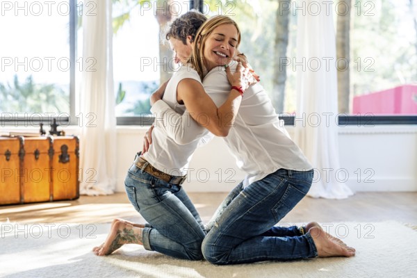 Side view of a man and a woman, both smiling, embrace warmly in a bright, airy room, expressing contentment and affection