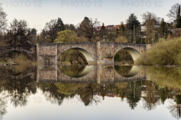 Stone bridge reflected in the calm water with surrounding nature, The historic Bartenwetz stone bridge of Melsungen