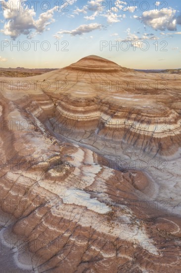Stunning aerial shot capturing the intricate layers and rolling hills of bentonite clay in Utah's rugged landscape, highlighted by warm sunset hues