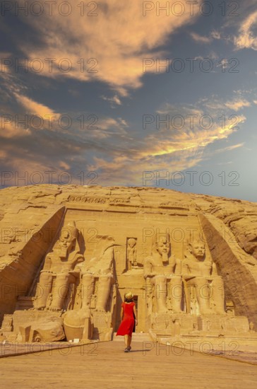 A European tourist in red dress walking towards the Abu Simbel Temple in southern Egypt in Nubia next to Lake Nasser. Temple of Pharaoh Ramses II, travel lifestyle