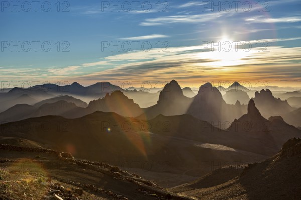 Sunbeams break through the haze over a mountain landscape at sunset, The landscape of the Ahaggar Mountains in the Sahara in Algeria